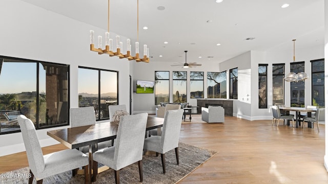 dining room with ceiling fan with notable chandelier and light hardwood / wood-style floors