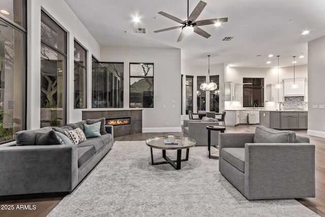 living room featuring hardwood / wood-style flooring, sink, and ceiling fan with notable chandelier