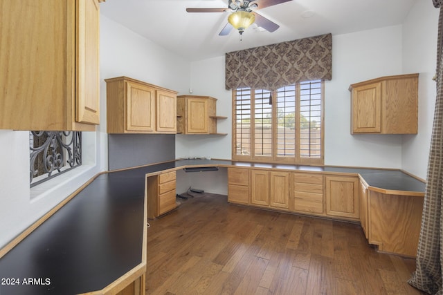 unfurnished office with dark hardwood / wood-style flooring, built in desk, and ceiling fan