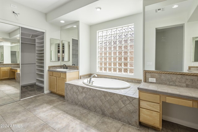 bathroom featuring vanity, tiled bath, and tile patterned flooring