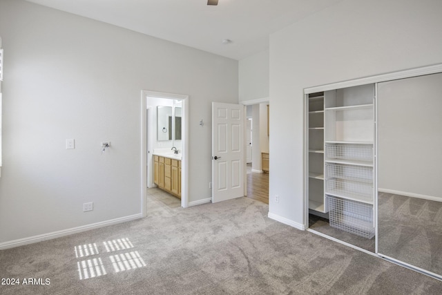 unfurnished bedroom with sink, light carpet, ensuite bath, and a closet