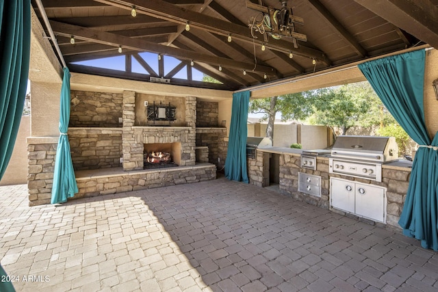 view of patio featuring a gazebo, an outdoor kitchen, a grill, and an outdoor stone fireplace