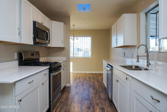 kitchen with sink, decorative light fixtures, white cabinetry, appliances with stainless steel finishes, and dark hardwood / wood-style flooring