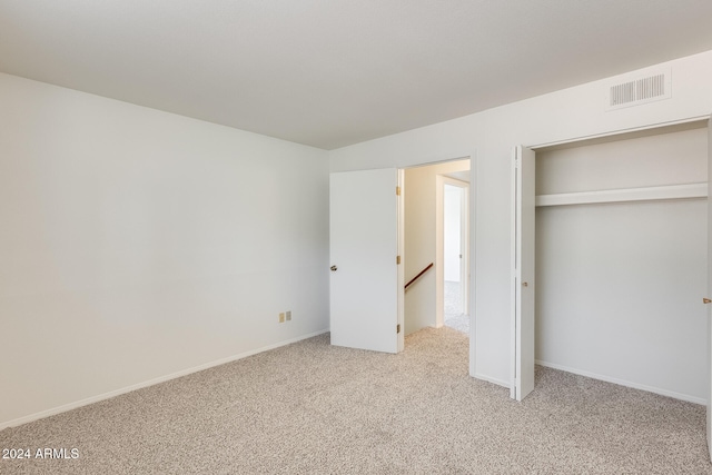 unfurnished bedroom with light colored carpet and a closet