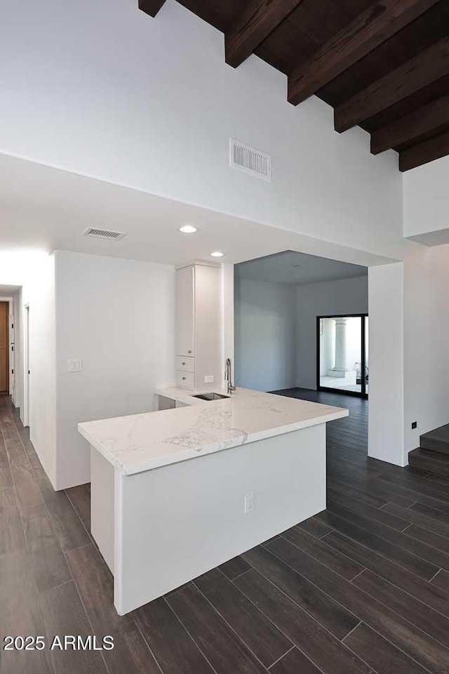 kitchen featuring white cabinets, sink, light stone counters, wooden ceiling, and beam ceiling