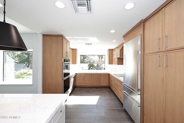 kitchen with high quality fridge, light stone counters, plenty of natural light, and dark hardwood / wood-style flooring