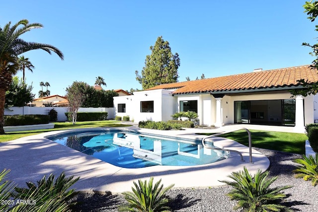 rear view of property with a fenced in pool and a lawn