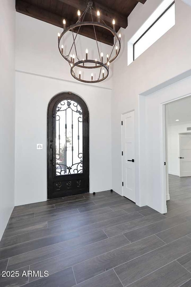 foyer entrance with an inviting chandelier, beamed ceiling, a high ceiling, and wood ceiling