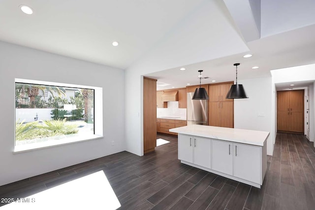 kitchen featuring hanging light fixtures, white cabinets, tasteful backsplash, a kitchen island, and lofted ceiling