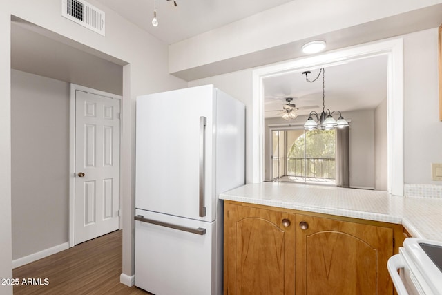 kitchen with white refrigerator, stove, dark hardwood / wood-style floors, and pendant lighting