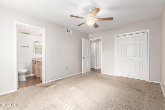 unfurnished bedroom featuring light colored carpet, a closet, ceiling fan, and ensuite bathroom