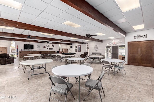 dining room featuring brick wall, a paneled ceiling, and beam ceiling