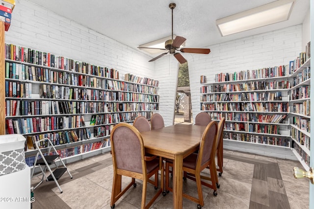 dining area featuring brick wall, a textured ceiling, and ceiling fan