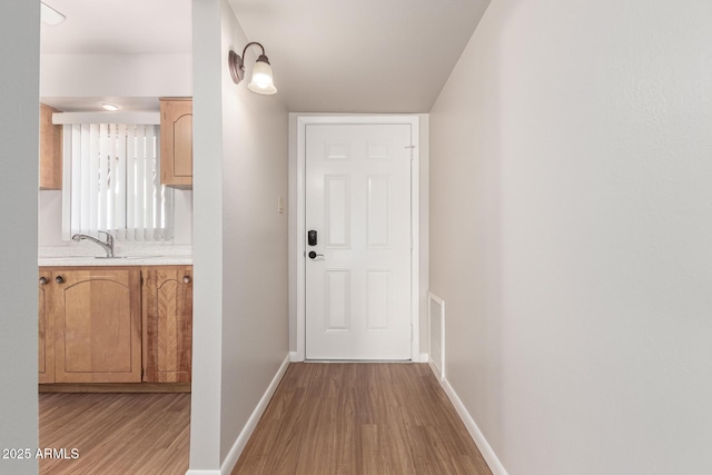 corridor featuring sink and light wood-type flooring