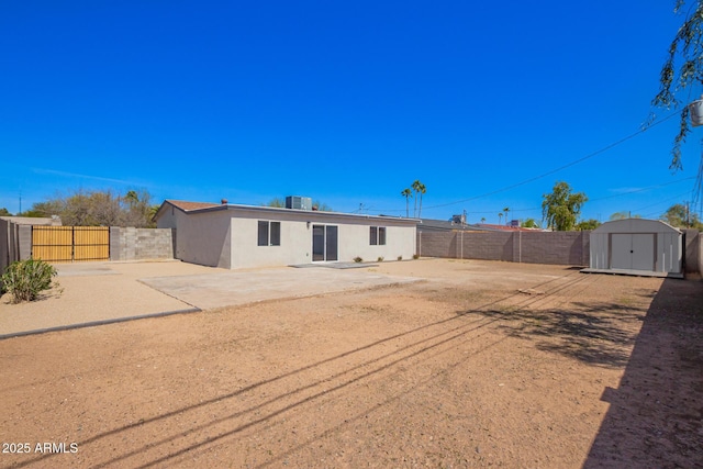 3249 E Nisbet Rd, Phoenix, AZ 85032 - back of house featuring a storage unit, stucco siding, central AC, a fenced backyard, and an outdoor structure