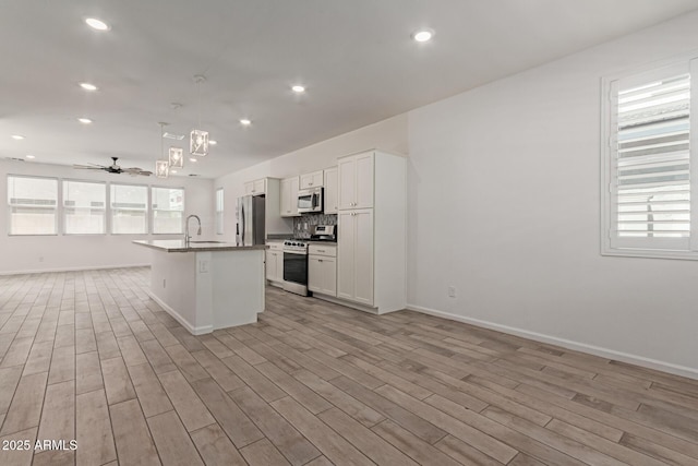 1857 W 22nd Ave, Apache Junction, AZ 85120 - kitchen featuring stainless steel appliances, open floor plan, light wood-style flooring, a ceiling fan, and baseboards