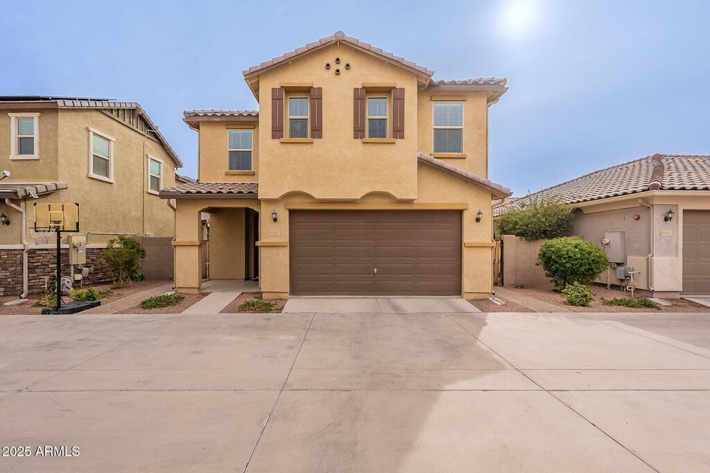 mediterranean / spanish house featuring stucco siding, concrete driveway, a tile roof, and an attached garage