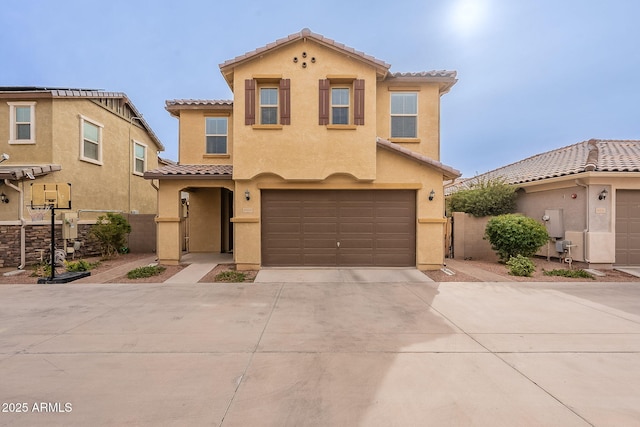 mediterranean / spanish house featuring stucco siding, concrete driveway, a tile roof, and an attached garage