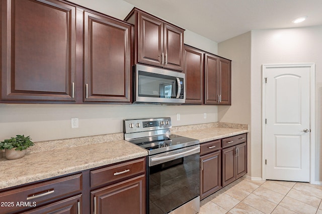 kitchen featuring stainless steel appliances, light tile patterned flooring, light countertops, baseboards, and dark brown cabinets