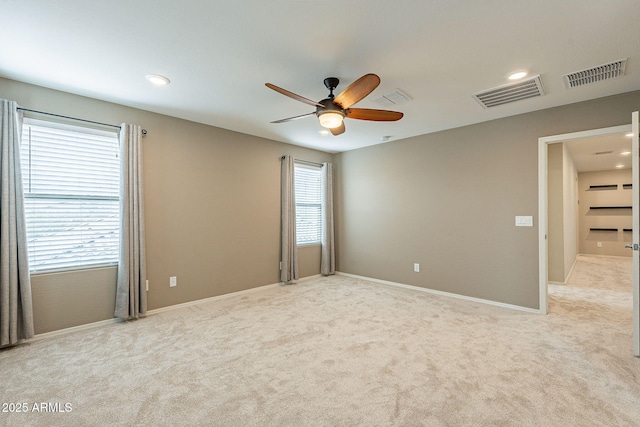 unfurnished room featuring light carpet, visible vents, baseboards, and a ceiling fan