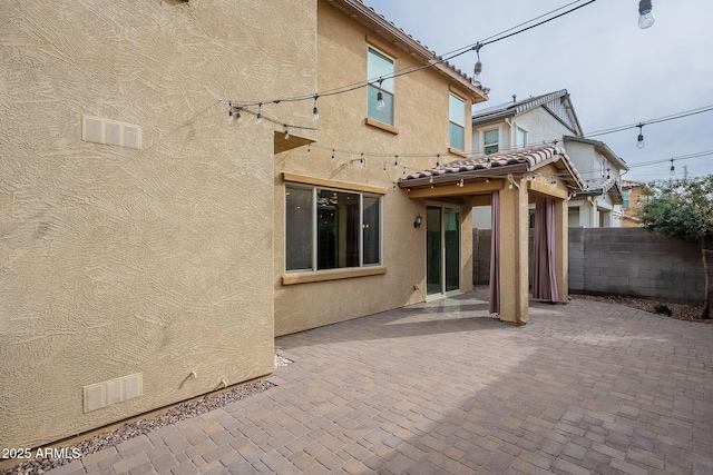 rear view of property with a patio area, stucco siding, a tiled roof, and fence