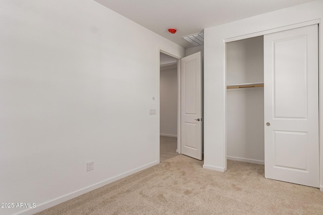 unfurnished bedroom with light carpet, a closet, and baseboards