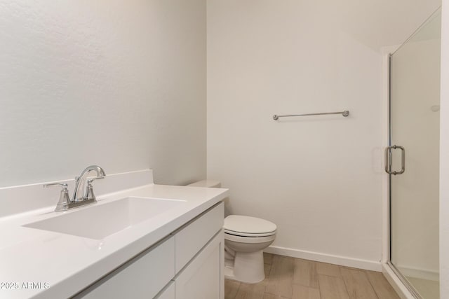 full bathroom with toilet, a shower stall, vanity, and baseboards