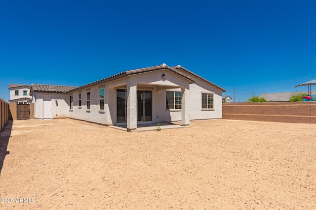 back of house featuring a fenced backyard, a tile roof, a patio, and stucco siding