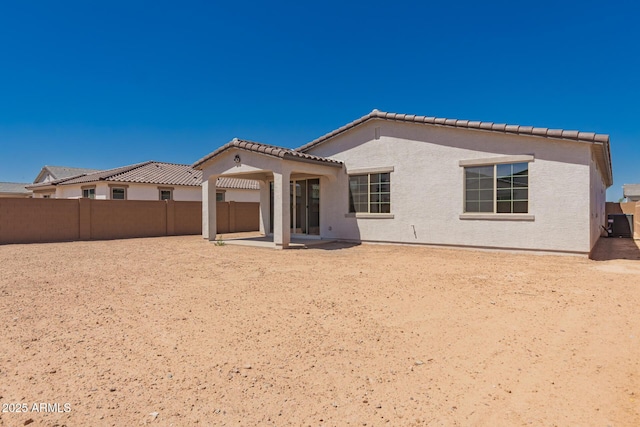 rear view of property with a tile roof, fence, a patio, and stucco siding