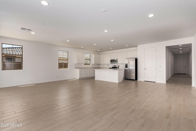 unfurnished living room with light wood-style floors, recessed lighting, visible vents, and baseboards
