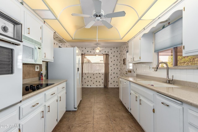 kitchen with sink, white appliances, light tile patterned floors, ceiling fan, and white cabinets