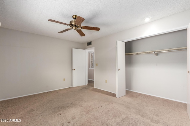 unfurnished bedroom featuring a textured ceiling, light colored carpet, a closet, and ceiling fan