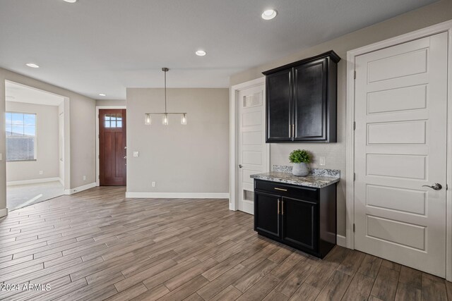 kitchen with pendant lighting, light stone countertops, and hardwood / wood-style floors