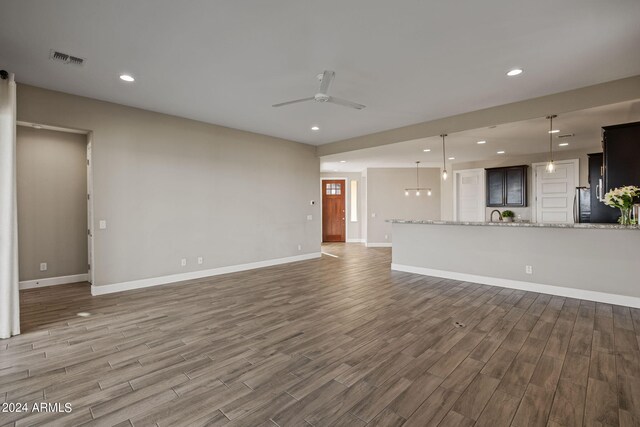 unfurnished living room featuring ceiling fan, hardwood / wood-style flooring, and sink