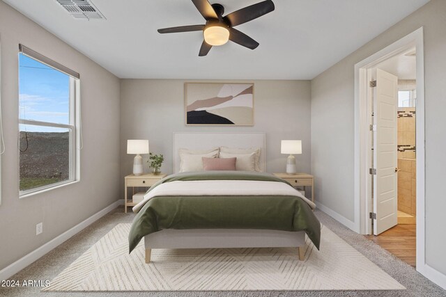 bedroom with light hardwood / wood-style flooring, ensuite bath, and ceiling fan