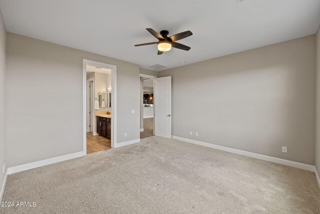 unfurnished bedroom featuring ceiling fan, ensuite bath, and light carpet