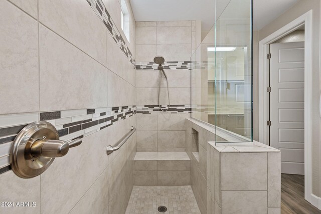 bathroom featuring hardwood / wood-style flooring, tile walls, and a tile shower