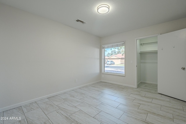 unfurnished bedroom featuring a walk in closet and a closet