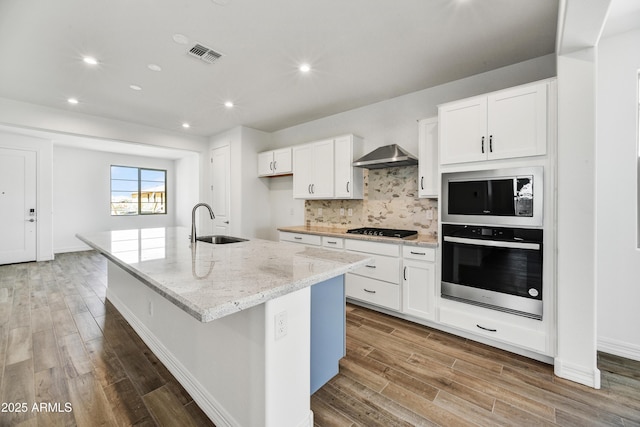 kitchen featuring white cabinetry, oven, a kitchen island with sink, black gas stovetop, and exhaust hood