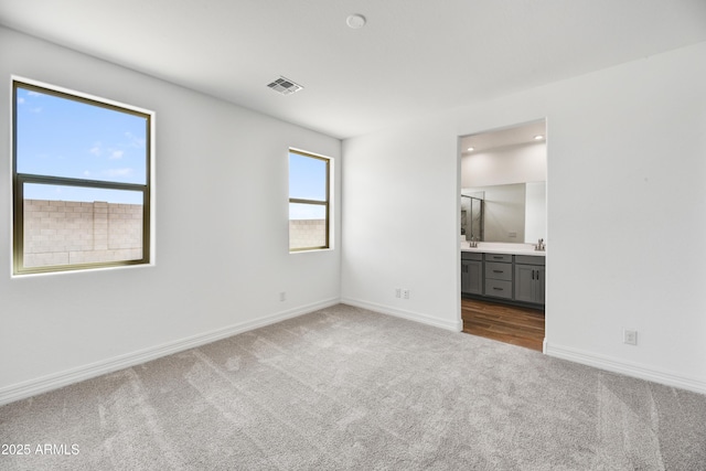 unfurnished bedroom with ensuite bathroom, carpet flooring, and sink