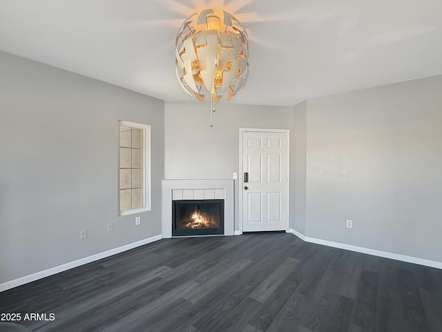 unfurnished living room with a lit fireplace, baseboards, and dark wood-style flooring