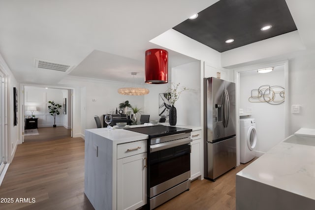 8317 E Orange Blossom Ln, Scottsdale, AZ 85250 - kitchen with stainless steel appliances, washer / clothes dryer, light wood-type flooring, white cabinetry, and light countertops