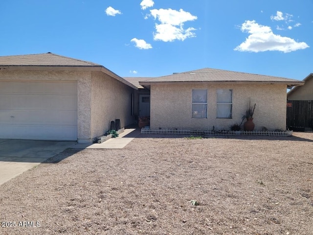 ranch-style house with a garage, concrete driveway, fence, and stucco siding