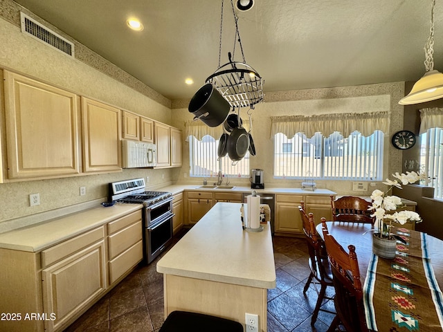 kitchen featuring light countertops, white microwave, light brown cabinets, a sink, and double oven range