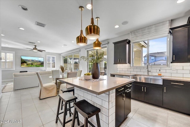 kitchen with a center island, decorative light fixtures, a healthy amount of sunlight, and sink