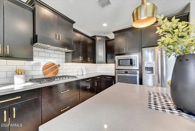 kitchen featuring decorative backsplash, dark brown cabinetry, decorative light fixtures, and appliances with stainless steel finishes