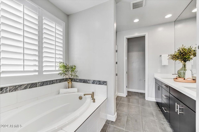 bathroom with tile patterned floors, tiled bath, and vanity