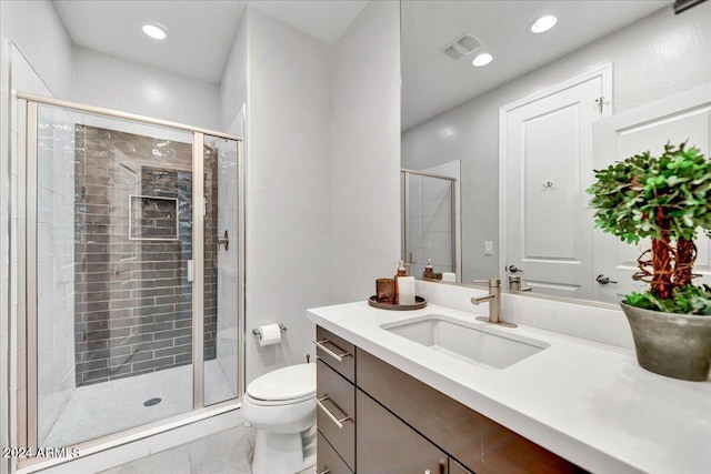 bathroom with tile patterned floors, vanity, toilet, and a shower with shower door