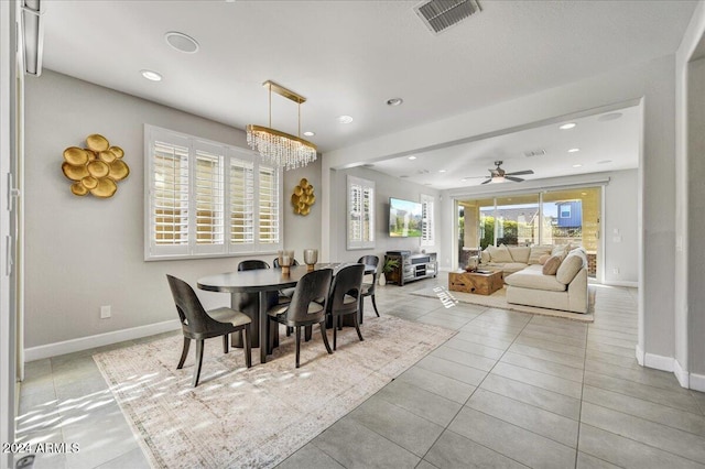 tiled dining room with ceiling fan with notable chandelier