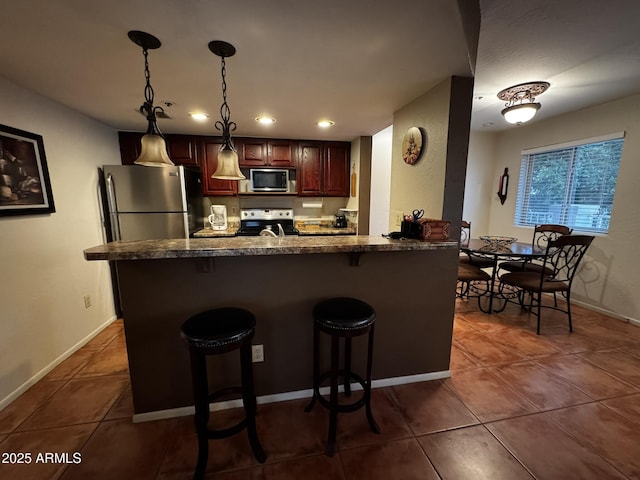 12123 W Bell Rd Unit 337, Surprise, AZ 85378 - kitchen featuring appliances with stainless steel finishes, a breakfast bar area, dark tile patterned floors, recessed lighting, and a peninsula